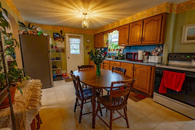 40 Merrow Rd, Auburn, ME 04210 - kitchen with electric range, freestanding refrigerator, brown cabinets, dark countertops, and a textured ceiling
