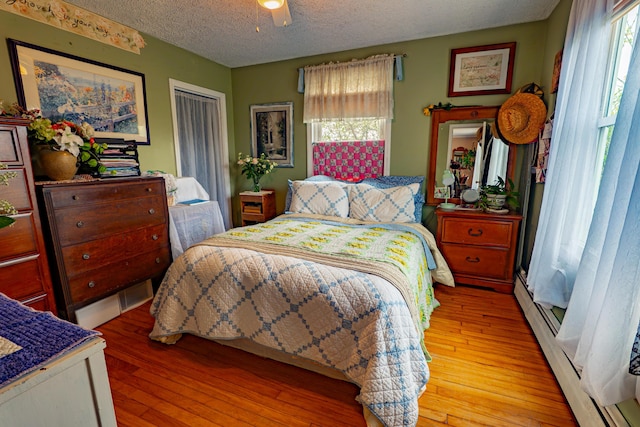 40 Merrow Rd, Auburn, ME 04210 - bedroom with light wood finished floors, a baseboard heating unit, a textured ceiling, and a ceiling fan