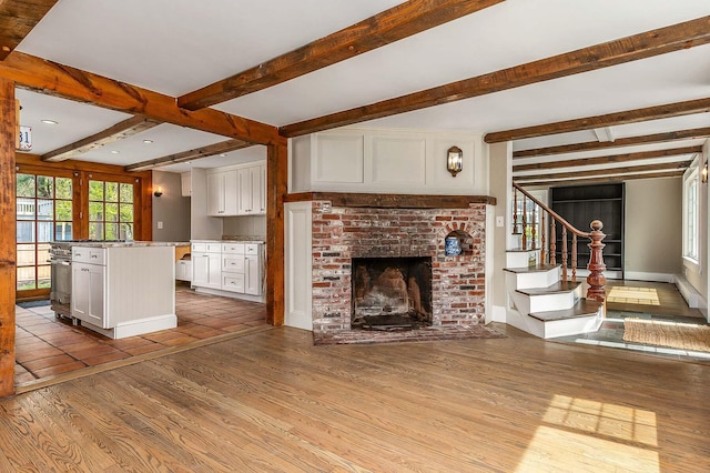 456 Ferry Rd, Saco, ME 04072 - unfurnished living room featuring wood finished floors, beamed ceiling, a fireplace, stairs, and baseboards