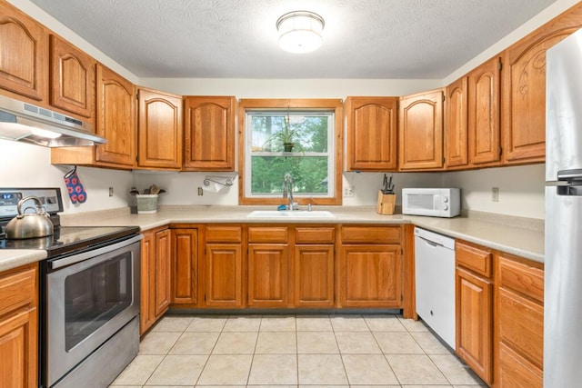 184 Long St, Limerick, ME 04048 - kitchen with appliances with stainless steel finishes, under cabinet range hood, brown cabinets, light countertops, and a textured ceiling