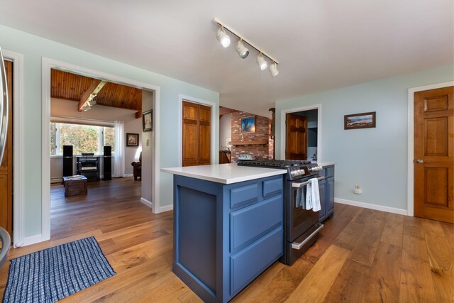 738 Litchfield Rd, Bowdoin, ME 04287 - kitchen featuring blue cabinets, stainless steel range with gas stovetop, light wood-type flooring, light countertops, and baseboards