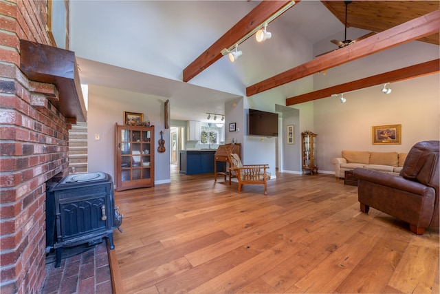 738 Litchfield Rd, Bowdoin, ME 04287 - living area with rail lighting, a wood stove, light wood finished floors, beam ceiling, and high vaulted ceiling