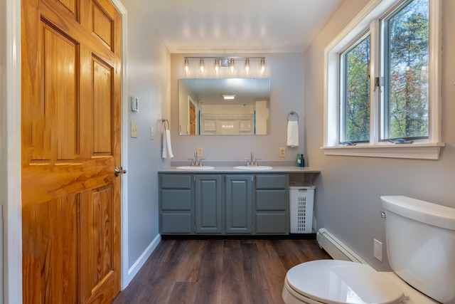 738 Litchfield Rd, Bowdoin, ME 04287 - bathroom featuring a baseboard heating unit, toilet, wood finished floors, double vanity, and baseboards