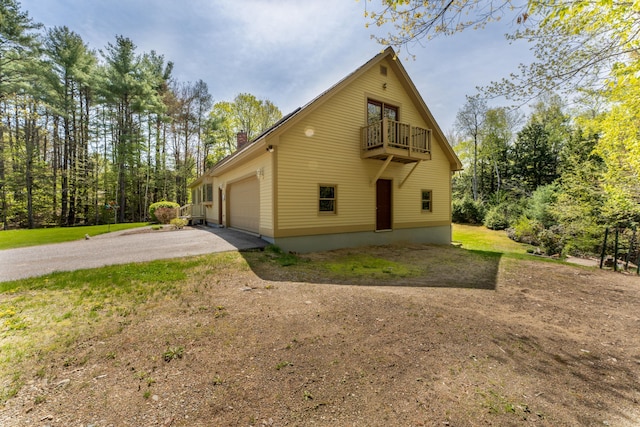 738 Litchfield Rd, Bowdoin, ME 04287 - view of home's exterior with a balcony, asphalt driveway, a garage, and a chimney