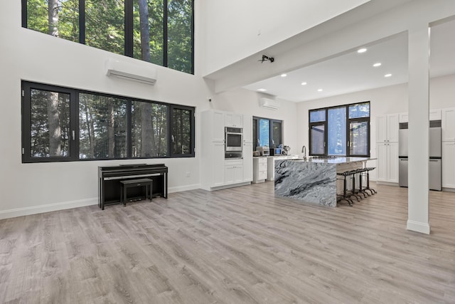 5 Zakelo Island Rd, Harrison, ME 04040 - living area featuring an AC wall unit, recessed lighting, light wood-style flooring, baseboards, and a high ceiling