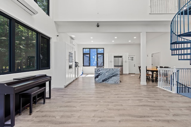 5 Zakelo Island Rd, Harrison, ME 04040 - foyer with light wood-type flooring, recessed lighting, a wall unit AC, a towering ceiling, and stairs