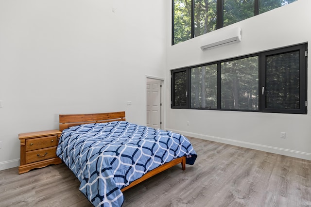 5 Zakelo Island Rd, Harrison, ME 04040 - bedroom with wood finished floors, baseboards, a high ceiling, and an AC wall unit