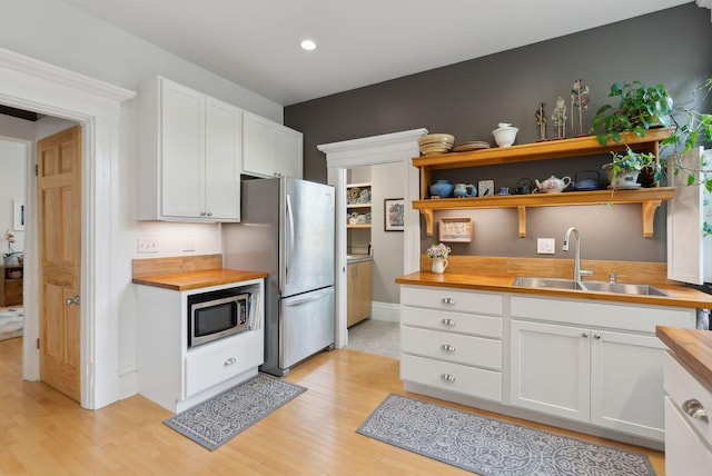 377 Cumberland Ave, Portland, ME 04101 - kitchen with butcher block countertops, stainless steel appliances, a sink, light wood-style flooring, and recessed lighting