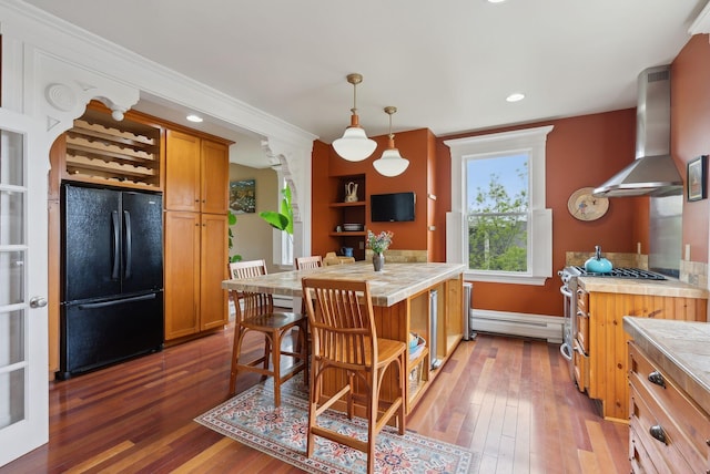 377 Cumberland Ave, Portland, ME 04101 - kitchen featuring freestanding refrigerator, wall chimney exhaust hood, hardwood / wood-style flooring, a baseboard heating unit, and brown cabinets