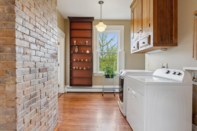 377 Cumberland Ave, Portland, ME 04101 - laundry room featuring light wood-style floors, washer and clothes dryer, baseboard heating, cabinet space, and brick wall