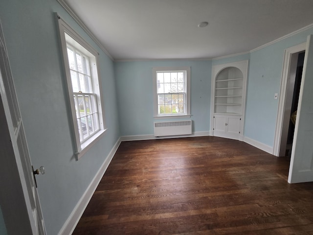 22 Summer St, Lubec, ME 04652 - empty room featuring radiator, dark wood-type flooring, built in shelves, crown molding, and baseboards