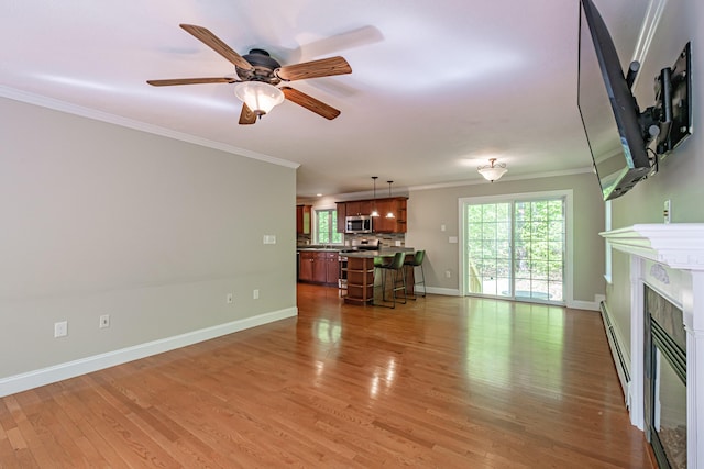 9 Eisenhower Ct, Naples, ME 04055 - unfurnished living room featuring ornamental molding, baseboards, light wood finished floors, a baseboard heating unit, and a glass covered fireplace