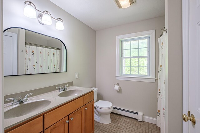 9 Eisenhower Ct, Naples, ME 04055 - full bath with a baseboard heating unit, tile patterned floors, double vanity, toilet, and baseboards