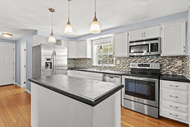 kitchen featuring stainless steel appliances, dark countertops, a sink, and backsplash
