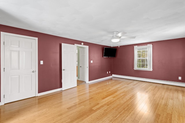 unfurnished bedroom with baseboard heating, light wood-style floors, baseboards, and a ceiling fan