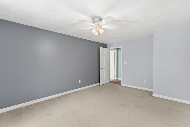 spare room featuring a ceiling fan, light colored carpet, and baseboards