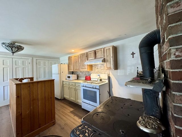 4 Main St, Saint Albans, ME 04971 - kitchen featuring white appliances, a wood stove, under cabinet range hood, dark wood-style flooring, and decorative backsplash