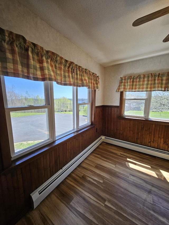 1377 Pushaw Rd, Glenburn, ME 04401 - empty room featuring wood finished floors, a textured ceiling, wooden walls, a wainscoted wall, and a baseboard radiator