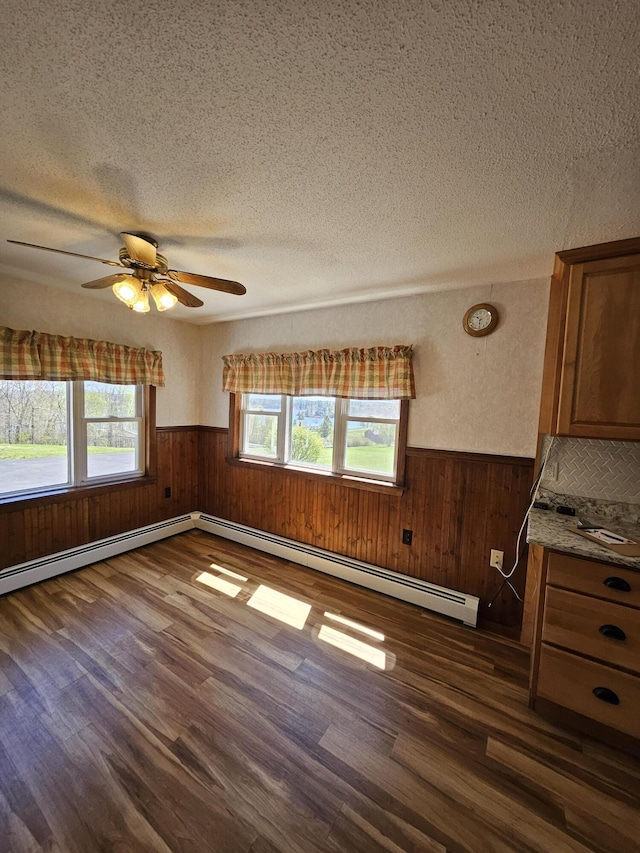 1377 Pushaw Rd, Glenburn, ME 04401 - unfurnished living room featuring dark wood-style flooring, a wainscoted wall, a textured ceiling, wooden walls, and a baseboard radiator