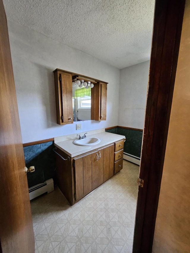 1377 Pushaw Rd, Glenburn, ME 04401 - bathroom with baseboard heating, tile patterned floors, a textured ceiling, a wainscoted wall, and vanity