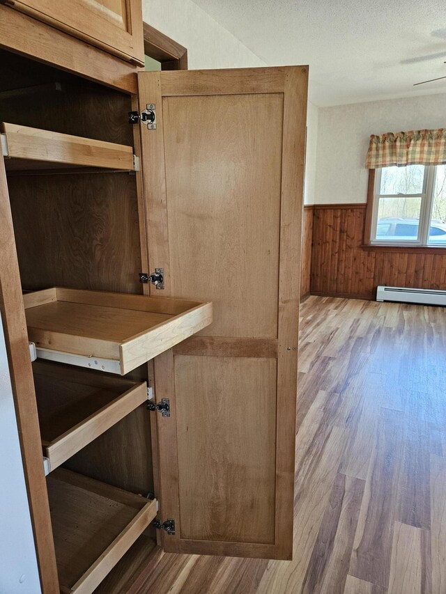 1377 Pushaw Rd, Glenburn, ME 04401 - detailed view of wood finished floors, a wainscoted wall, wood walls, and a baseboard heating unit