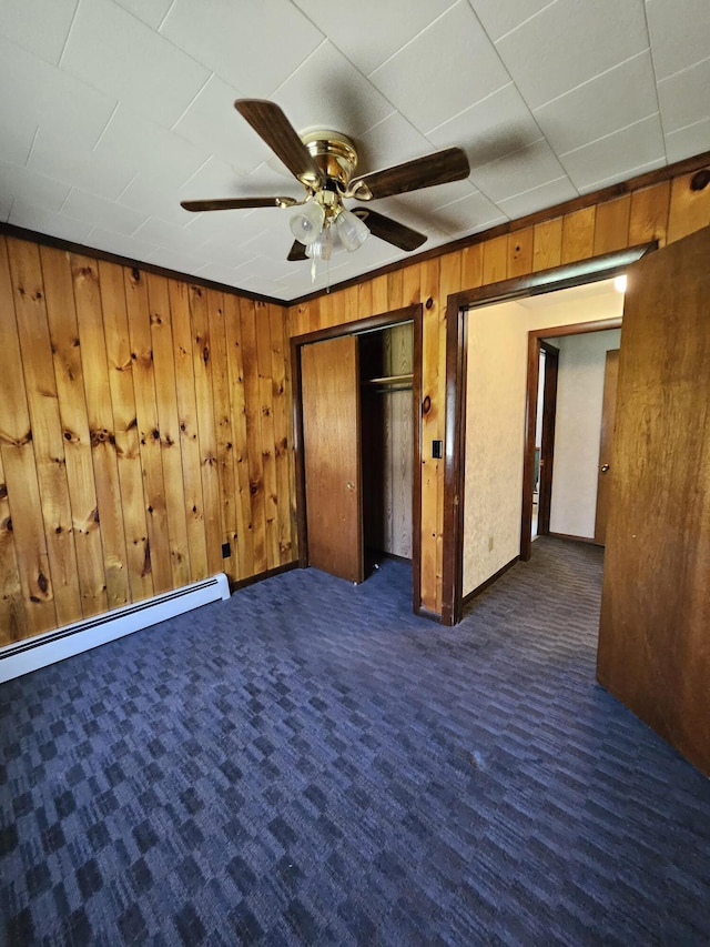 1377 Pushaw Rd, Glenburn, ME 04401 - unfurnished bedroom with wooden walls, carpet, a closet, ceiling fan, and a baseboard heating unit