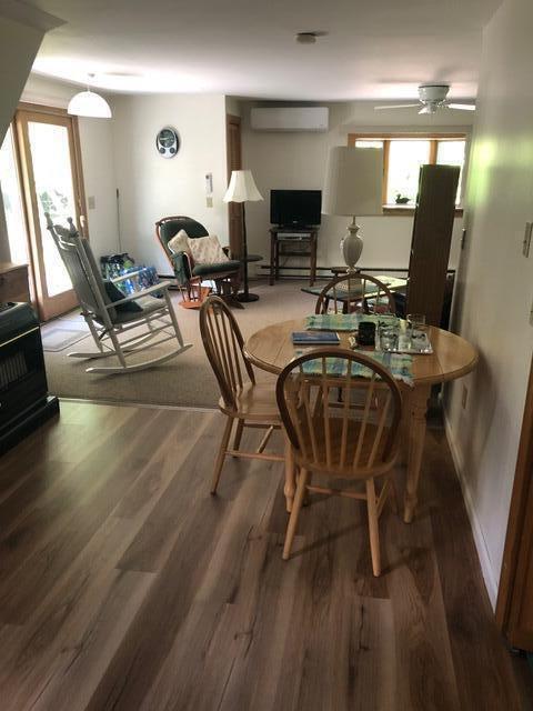11 Beethoven Ln, Enfield, ME 04493 - dining space featuring an AC wall unit, wood finished floors, and a ceiling fan