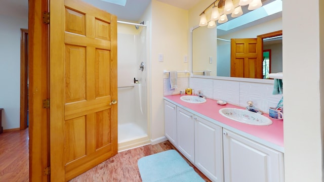 11 Beethoven Ln, Enfield, ME 04493 - full bathroom with a walk in shower, wood finished floors, double vanity, and tasteful backsplash