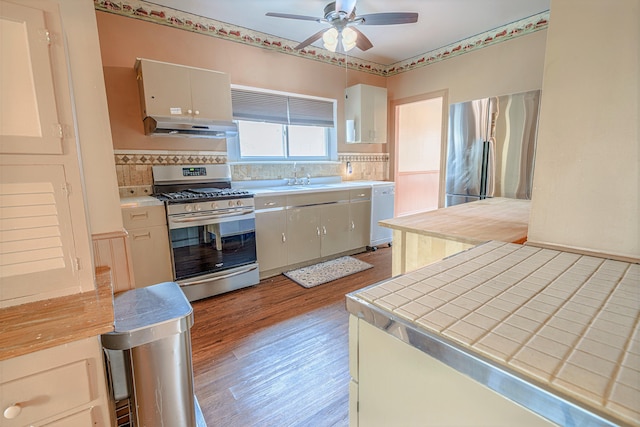 77 Cottage St, Bangor, ME 04401 - kitchen with appliances with stainless steel finishes, under cabinet range hood, light wood finished floors, a ceiling fan, and tile countertops