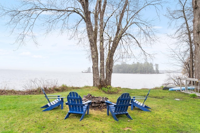 view of green lawn with a water view and an outdoor fire pit