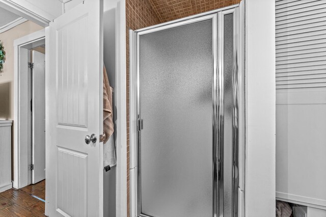 bathroom with a stall shower and wood finished floors