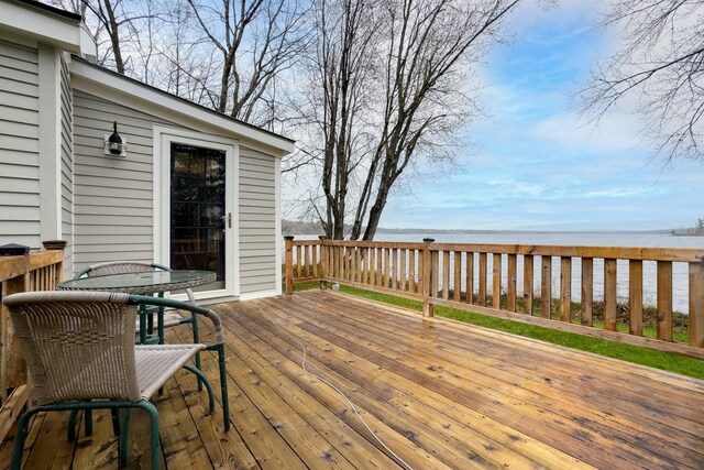 wooden terrace with a water view and outdoor dining area