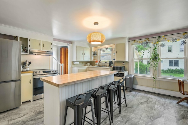 148 Water St, Randolph, ME 04346 - kitchen featuring stainless steel appliances, under cabinet range hood, light marble finish flooring, and butcher block countertops