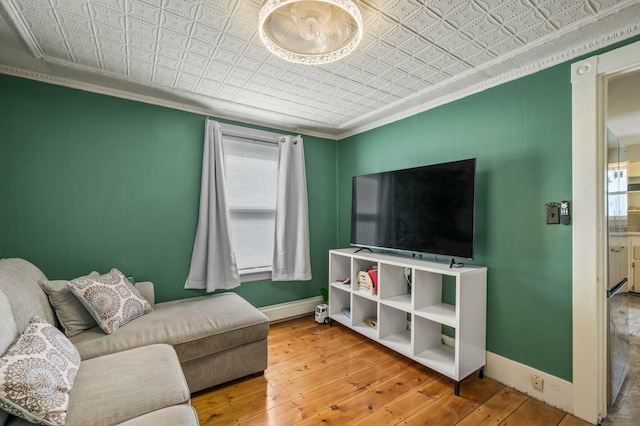 148 Water St, Randolph, ME 04346 - living room with an ornate ceiling, a baseboard heating unit, baseboards, crown molding, and hardwood / wood-style floors