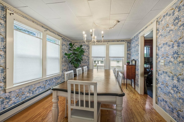 148 Water St, Randolph, ME 04346 - dining space with a baseboard heating unit, wallpapered walls, wood finished floors, a chandelier, and crown molding