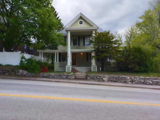 neoclassical / greek revival house featuring covered porch and fence