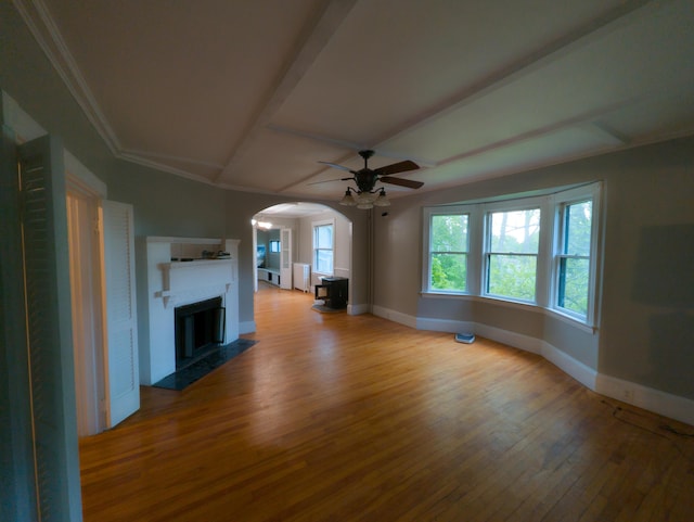 unfurnished living room with wood finished floors, arched walkways, baseboards, a ceiling fan, and a fireplace with flush hearth