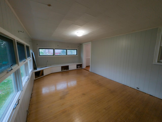unfurnished room featuring light wood-style floors, radiator, and wooden walls