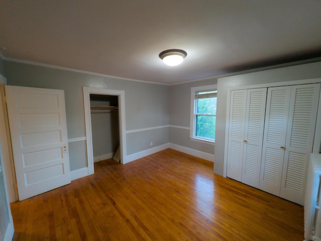 unfurnished bedroom featuring crown molding, wood finished floors, and baseboards