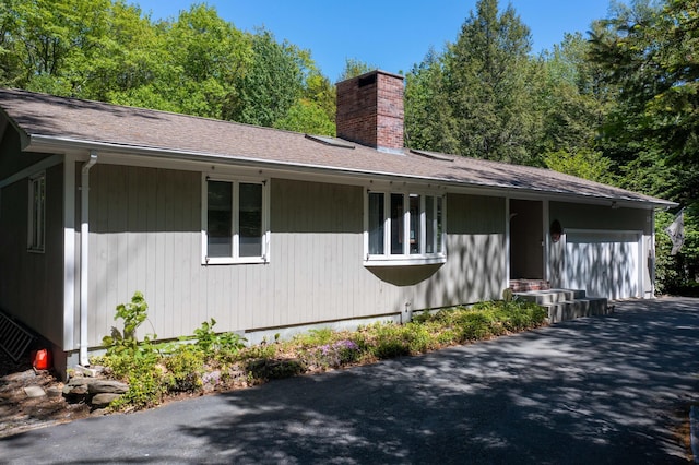 19 Brookside Dr, Falmouth, ME 04105 - view of side of property featuring a chimney, an attached garage, asphalt driveway, and roof with shingles