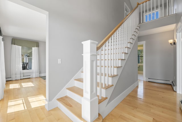 246 Coombs Rd, Brunswick, ME 04011 - stairway featuring wood finished floors, baseboards, a high ceiling, and a baseboard radiator