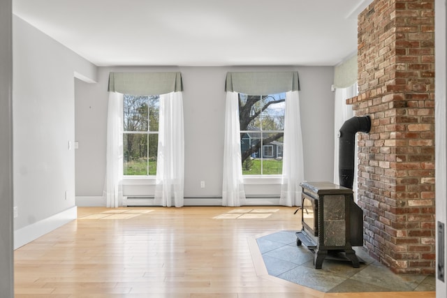 246 Coombs Rd, Brunswick, ME 04011 - unfurnished living room with wood finished floors, a wood stove, and a baseboard radiator