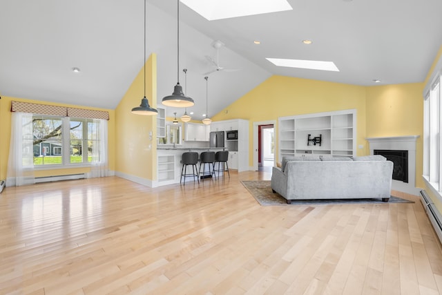 246 Coombs Rd, Brunswick, ME 04011 - living area featuring a skylight, high vaulted ceiling, a baseboard heating unit, a fireplace, and light wood-style flooring