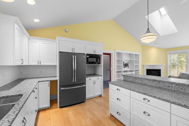 246 Coombs Rd, Brunswick, ME 04011 - kitchen featuring freestanding refrigerator, a skylight, black microwave, lofted ceiling, and white cabinetry