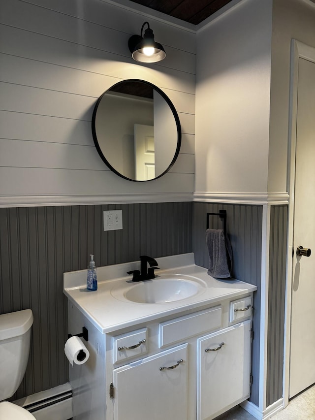 74 Fields Pond Rd, Holden, ME 04429 - half bath featuring baseboard heating, vanity, toilet, a wainscoted wall, and wallpapered walls