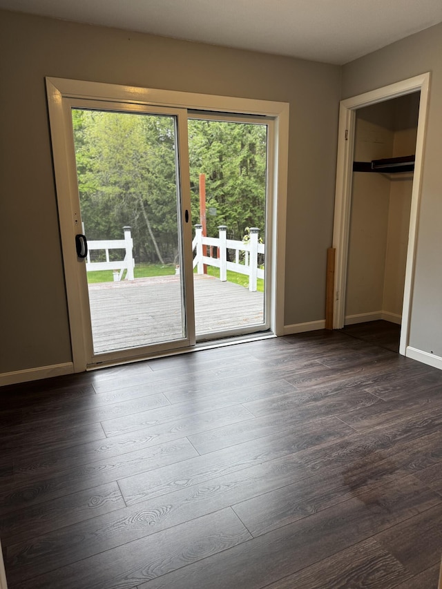 74 Fields Pond Rd, Holden, ME 04429 - unfurnished bedroom featuring access to outside, multiple windows, dark wood-type flooring, and baseboards