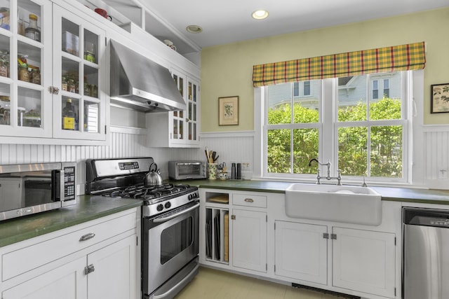 37 Mountain St, Camden, ME 04843 - kitchen with appliances with stainless steel finishes, wall chimney exhaust hood, a sink, a wainscoted wall, and healthy amount of natural light