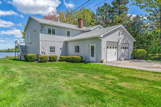 117 Pinkhams Cove Rd, Belgrade, ME 04917 - view of property exterior featuring a chimney, a shingled roof, a lawn, an attached garage, and stairway