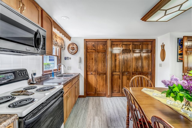 117 Pinkhams Cove Rd, Belgrade, ME 04917 - kitchen featuring range with electric stovetop, stainless steel microwave, a sink, light wood-type flooring, and brown cabinetry