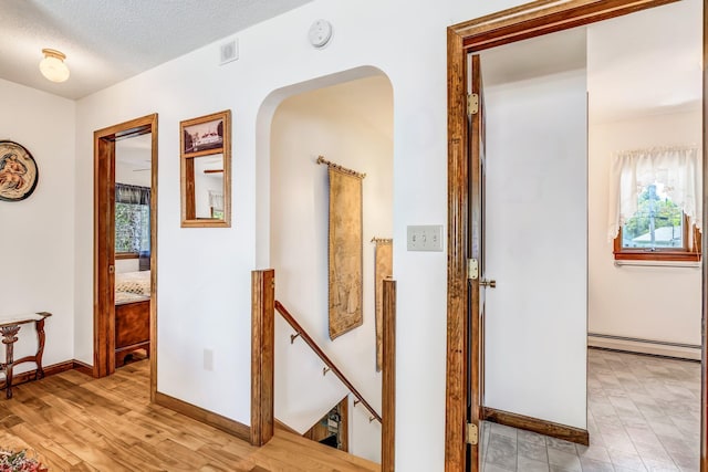 117 Pinkhams Cove Rd, Belgrade, ME 04917 - hall with a baseboard heating unit, an upstairs landing, arched walkways, baseboards, and a textured ceiling